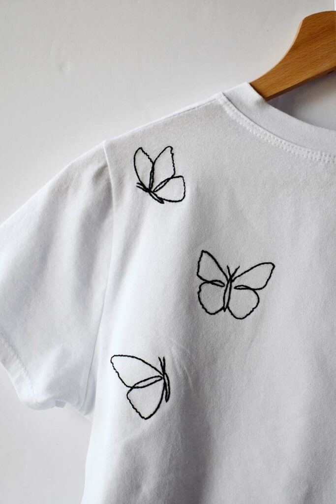 T-shirt bianche con farfalle ricamate a mano. Filo da ricamo nero, solo i contorni