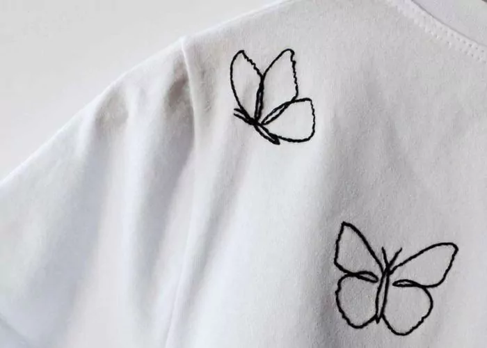 Profilo di farfalla nero ricamato su t-shirt bianca